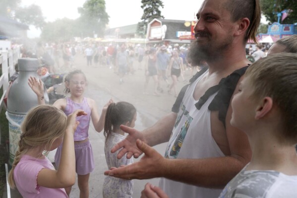 Fair-goers scorched by heartland heat wave take refuge under misters as some schools let out early